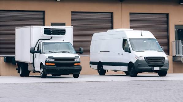 Refrigerated box truck and cargo van staged at loading docks